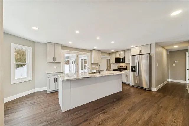 a kitchen with stainless steel appliances granite countertop a refrigerator and a stove top oven
