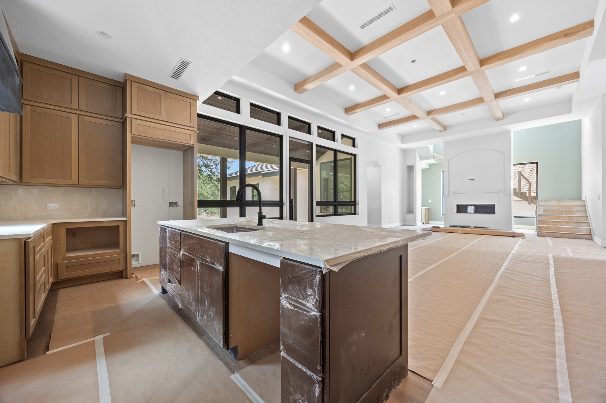 903 Flint Ridge Trail Georgetown, TX 78628 - Photo 12 of 39 Expansive kitchen and living area featuring a large center island with integrated sink, light wood-tone cabinetry, and a coffered ceiling with recessed lighting