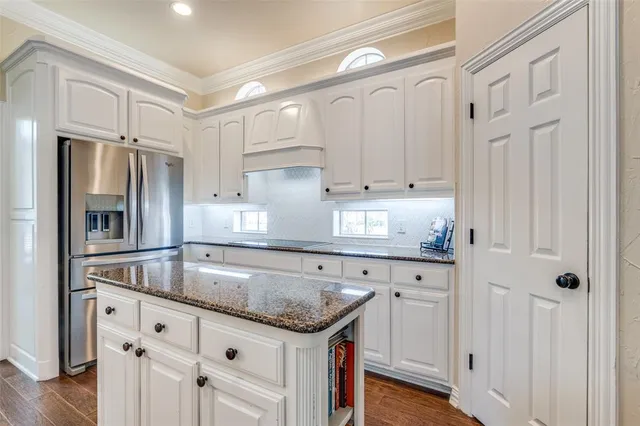 a kitchen with granite countertop white cabinets and refrigerator