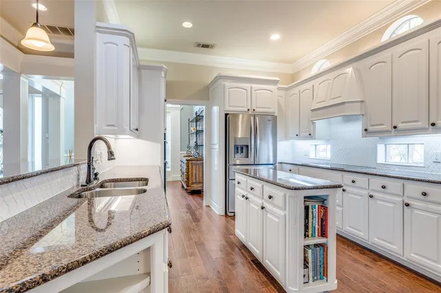 a kitchen with granite countertop a sink stainless steel appliances and white cabinets