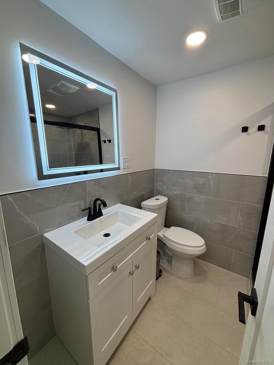 791 Longview Avenue Valley Stream, NY 11581 - Photo 17 of 33 Bathroom featuring tile walls, vanity, light tile patterned floors, and a stall shower