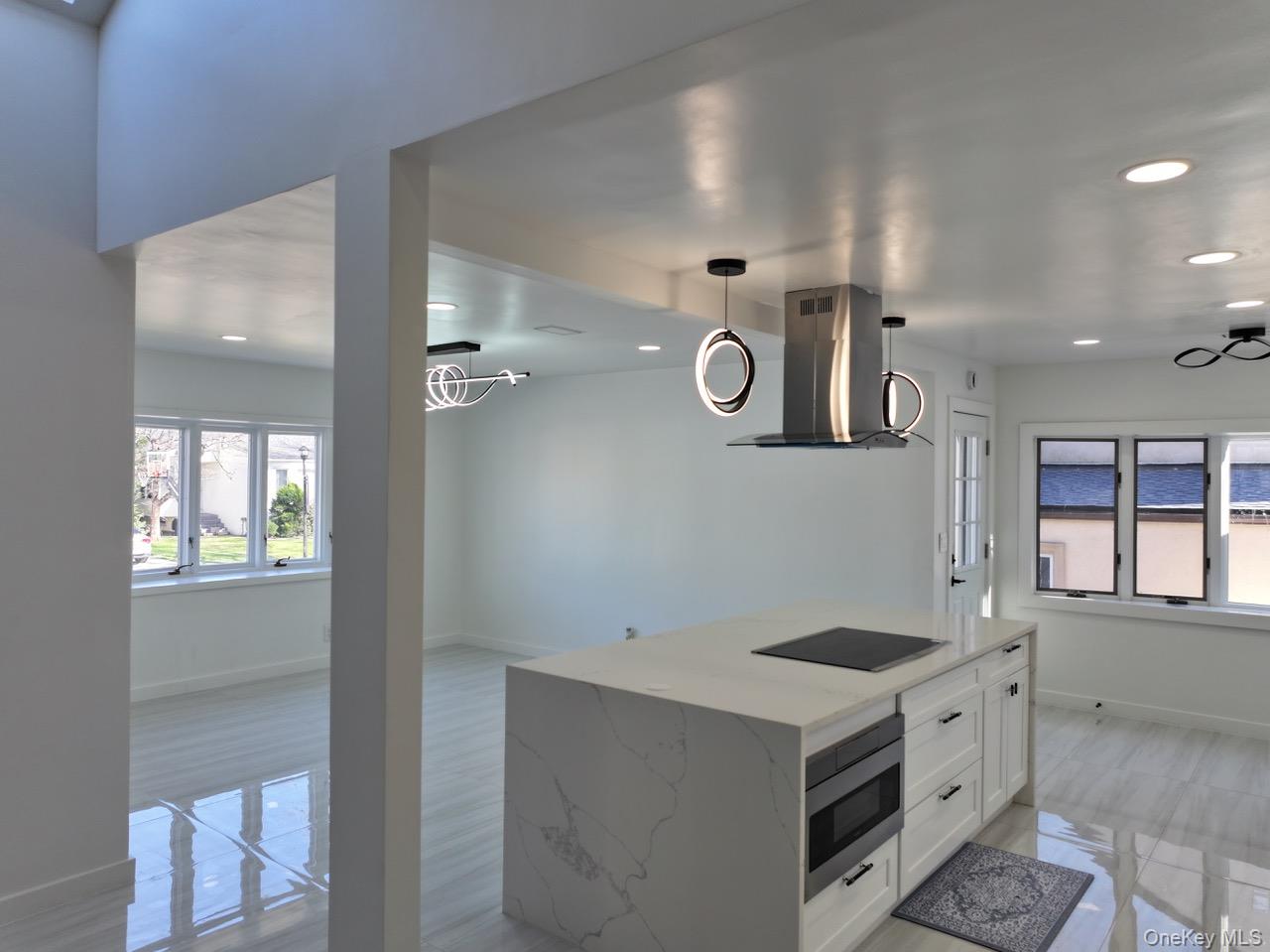791 Longview Avenue Valley Stream, NY 11581 - Photo 32 of 33 Kitchen with range hood, white cabinets, light stone countertops, stainless steel microwave, and a center island