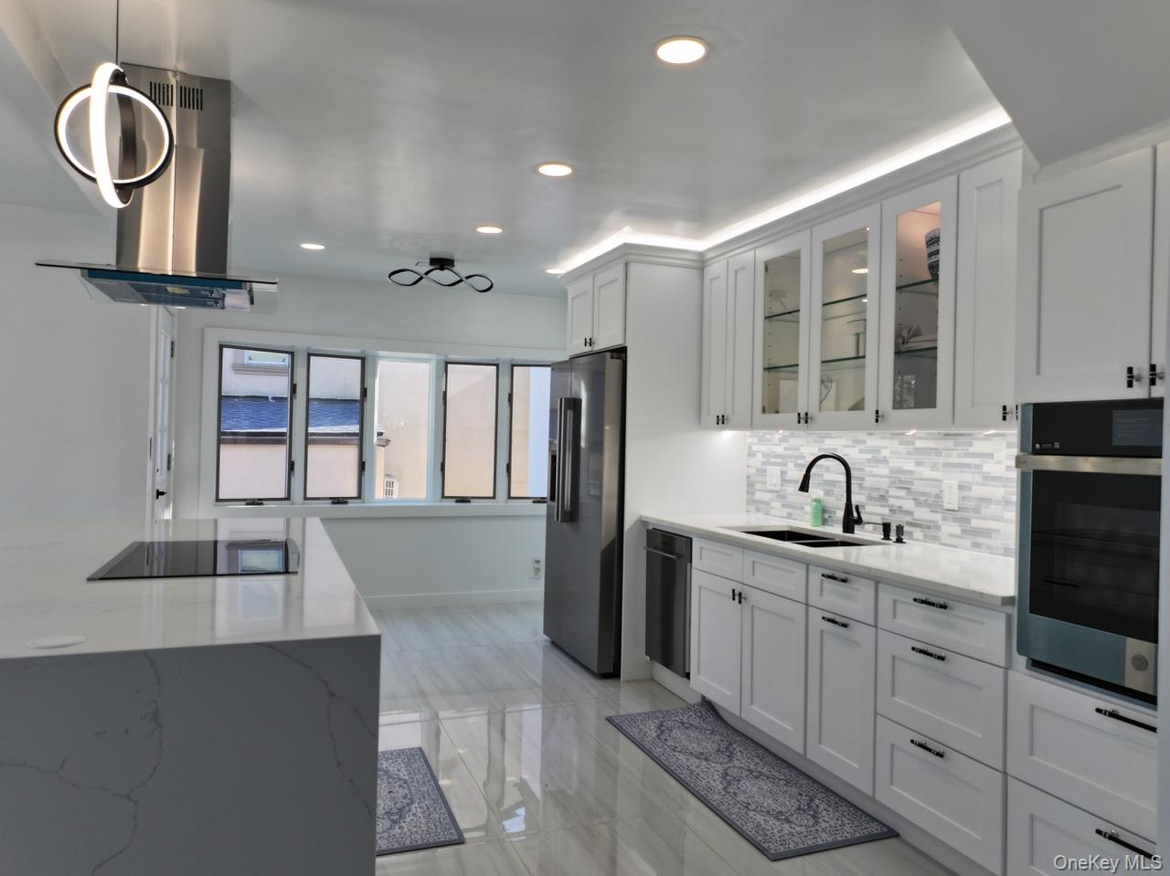 791 Longview Avenue Valley Stream, NY 11581 - Photo 33 of 33 Kitchen featuring range hood, light stone counters, stainless steel appliances, white cabinets, and glass fronted cabinets