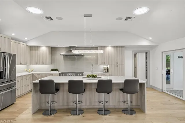 a kitchen with stainless steel appliances kitchen island granite countertop a refrigerator a stove a dining table and chairs