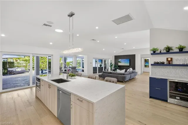 a living room with stainless steel appliances kitchen island a table chairs in it and a refrigerator