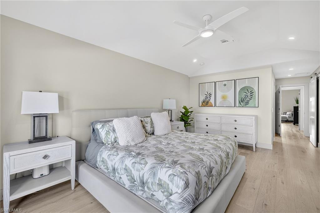 5215 Seashell Avenue Naples, FL 34103 - Photo 30 of 47 a spacious bedroom with a bed and a lamp