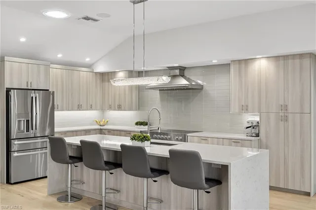 a kitchen with stainless steel appliances granite countertop a sink a stove a refrigerator and island with wooden floor