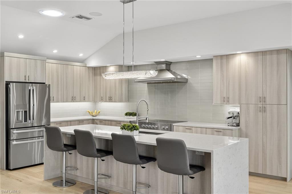 5215 Seashell Avenue Naples, FL 34103 - Photo 7 of 47 a kitchen with stainless steel appliances granite countertop a sink a stove a refrigerator and island with wooden floor