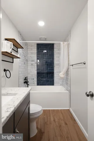 a bathroom with a granite countertop bathtub sink vanity mirror and toilet