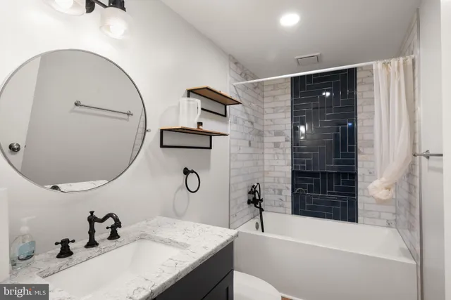 a bathroom with a granite countertop sink a mirror and a bathtub