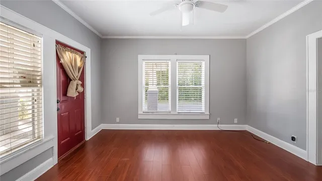 an empty room with wooden floor and windows