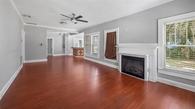 a view of a livingroom with wooden floor a fireplace and a window