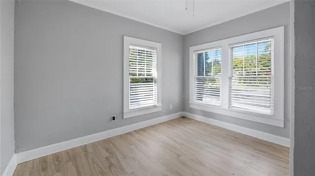 a view of an empty room with wooden floor and a window