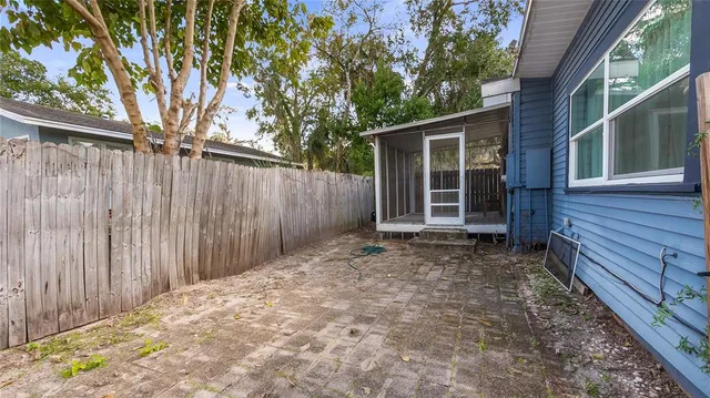 a view of a backyard with wooden fence and large trees