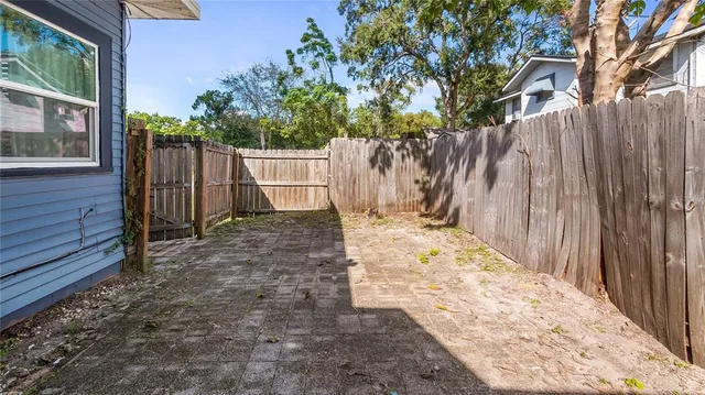 a view of a backyard with wooden fence and large trees