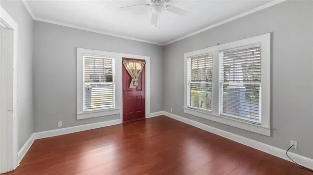a view of an empty room with wooden floor and a window
