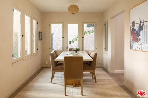 a dining room with wooden floor and windows