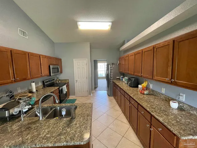 a kitchen with granite countertop a sink a stove and a wooden cabinets