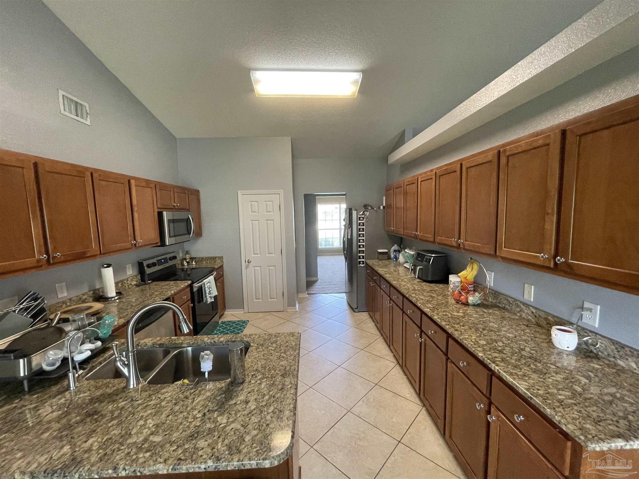 7025 Boo Lane Pensacola, FL 32526 - Photo 13 of 35 a kitchen with granite countertop a sink a stove and a wooden cabinets