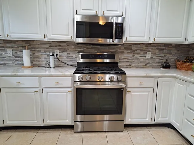 a kitchen with granite countertop white cabinets and stainless steel appliances