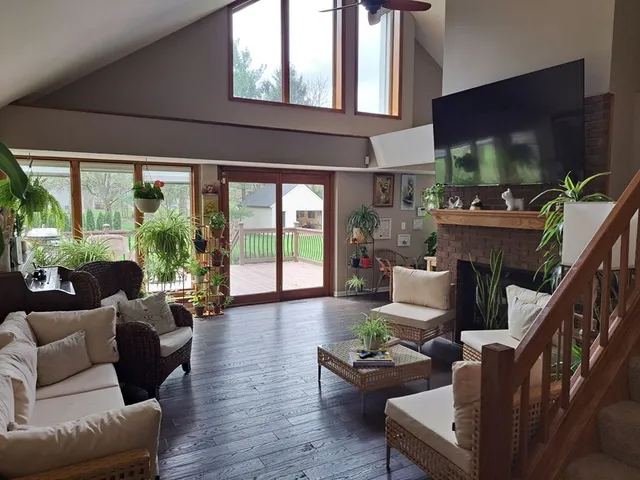 a living room with furniture a flat screen tv and floor to ceiling window