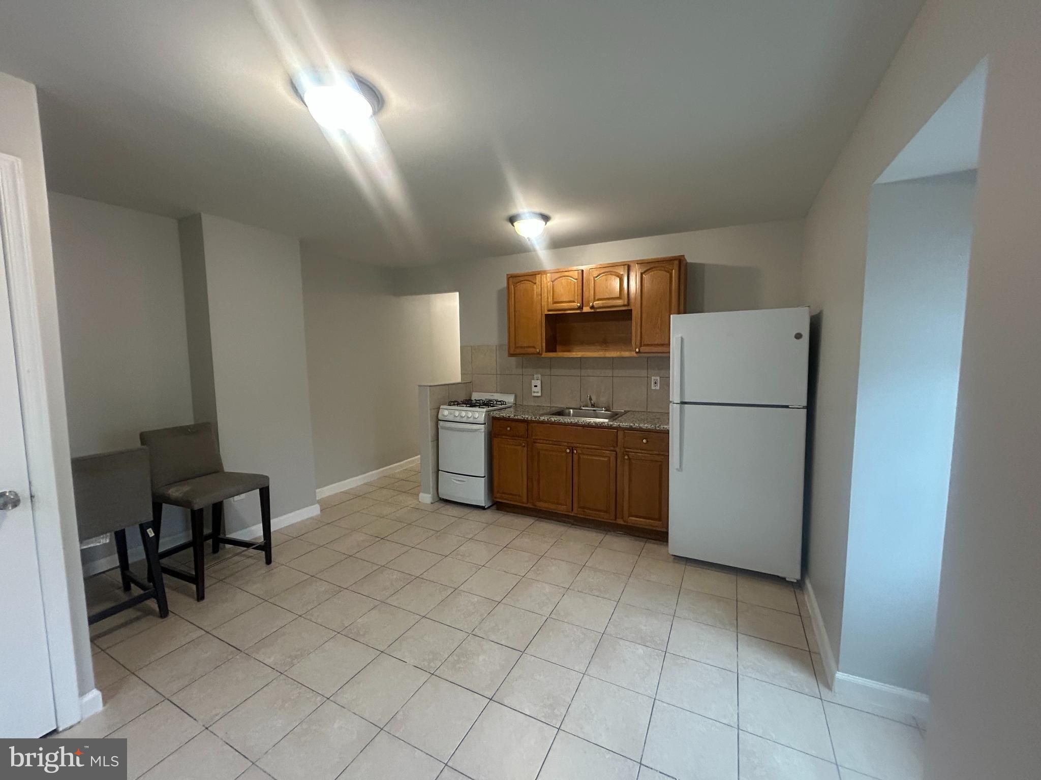 531 Brinton Street, Unit 3 Philadelphia, PA 19144 - Photo 5 of 9 a kitchen with refrigerator and chairs