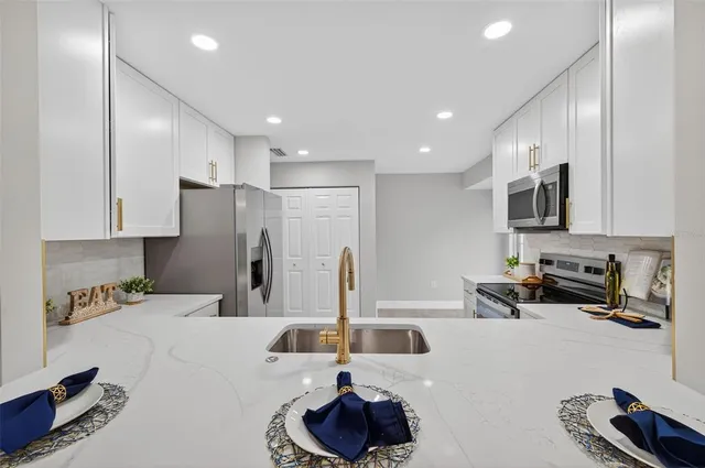 a kitchen with stainless steel appliances a sink a stove a microwave a refrigerator and cabinets