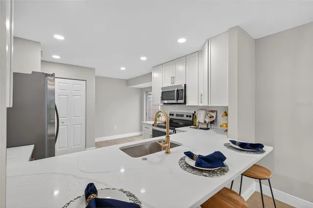 a kitchen with stainless steel appliances a sink a stove a refrigerator and cabinets