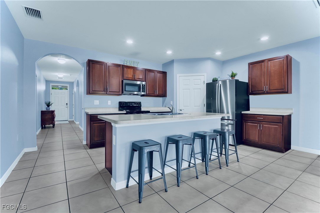 10357 Silver Pond Lane Lehigh Acres, FL 33936 - Photo 3 of 25 a kitchen with stainless steel appliances a refrigerator and a stove top oven