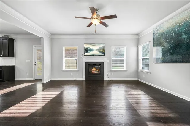 a view of an empty room with wooden floor fireplace and a window
