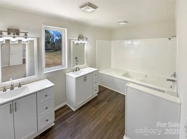 a bathroom with a double vanity sink a mirror and a bathtub