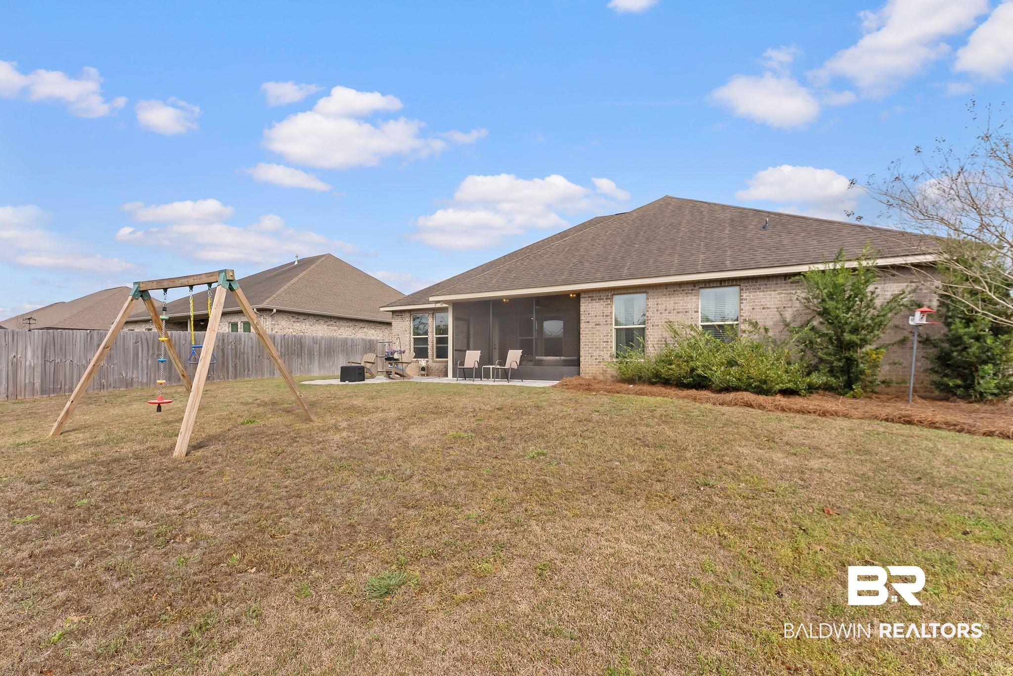 7015 Rocky Rd Loop Gulf Shores, AL 36542 - Photo 37 of 41 Back of house with a sunroom, a fenced backyard, brick siding, and a shingled roof