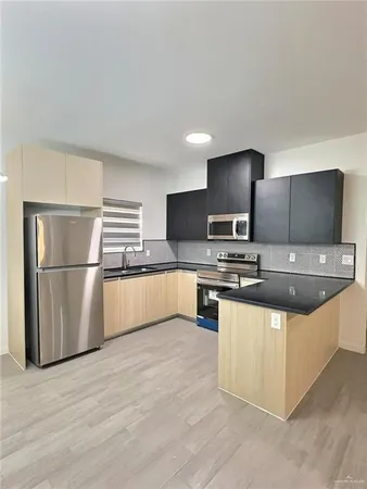 a large kitchen with stainless steel appliances a large counter top a sink a window and a couch