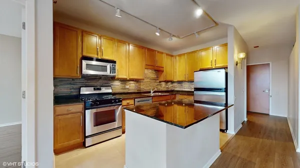 a kitchen with stainless steel appliances granite countertop a sink a stove and a refrigerator