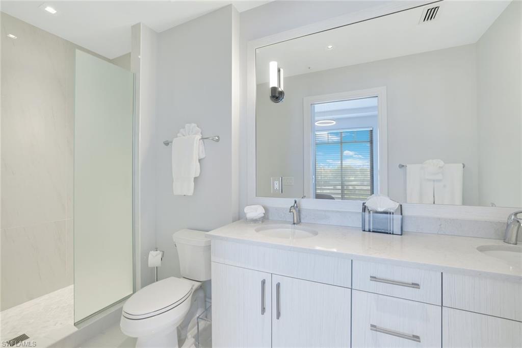101 8th Street South, Unit 301 Naples, FL 34102 - Photo 11 of 17 a bathroom with double sink a toilet a shower and a mirror