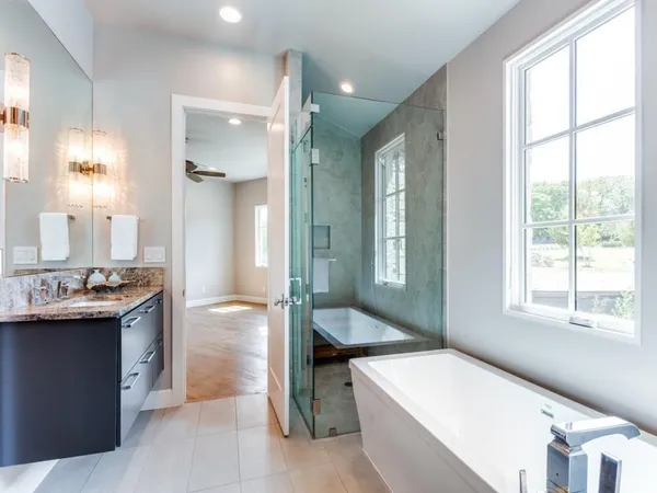 a spacious bathroom with a tub sink and mirror