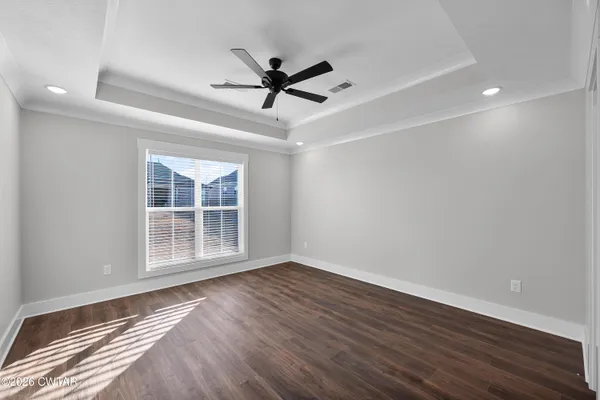 a view of empty room with wooden floor and fan
