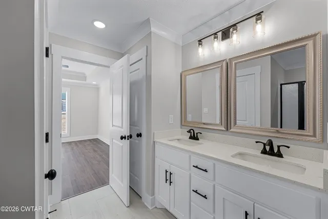 a bathroom with double vanity sinks a mirror and a shower