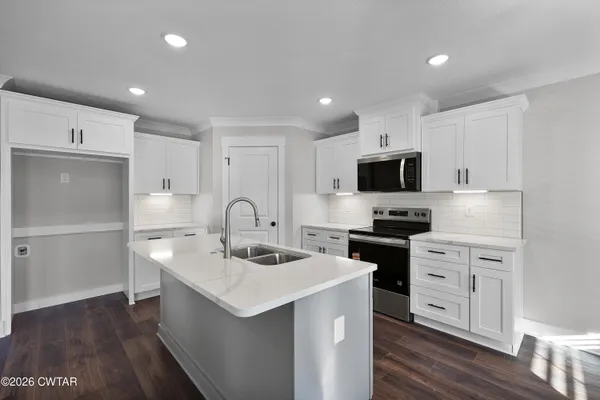 a large kitchen with stainless steel appliances a large counter top and a wooden floors