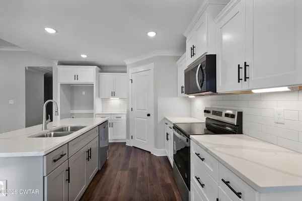 a kitchen with a sink a stove a refrigerator and white cabinets