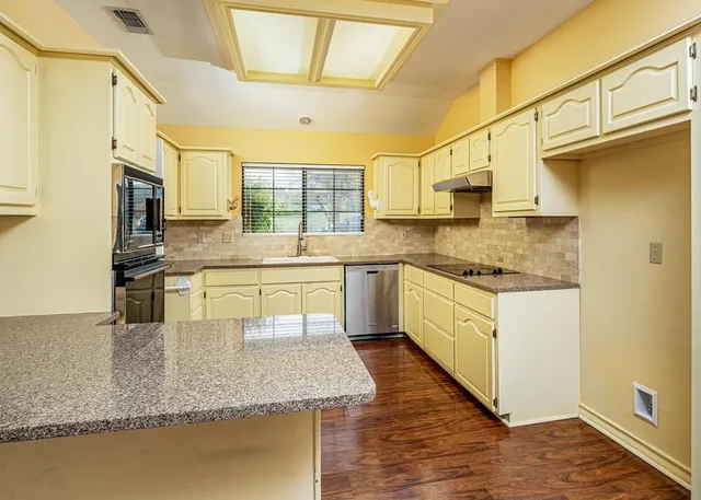 a kitchen with stainless steel appliances granite countertop a sink a stove counter space and cabinets