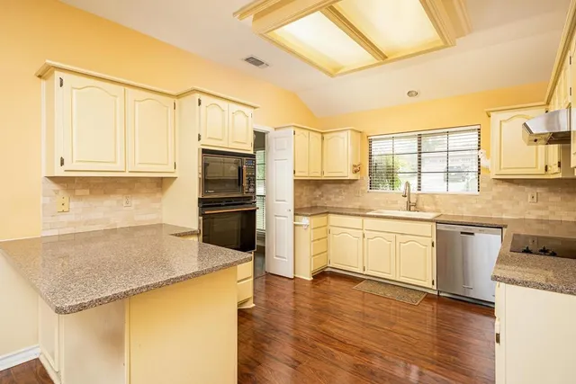 a kitchen with granite countertop a sink appliances cabinets and counter space