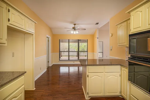 a open kitchen with granite countertop a stove top oven a sink dishwasher cabinets and wooden floor