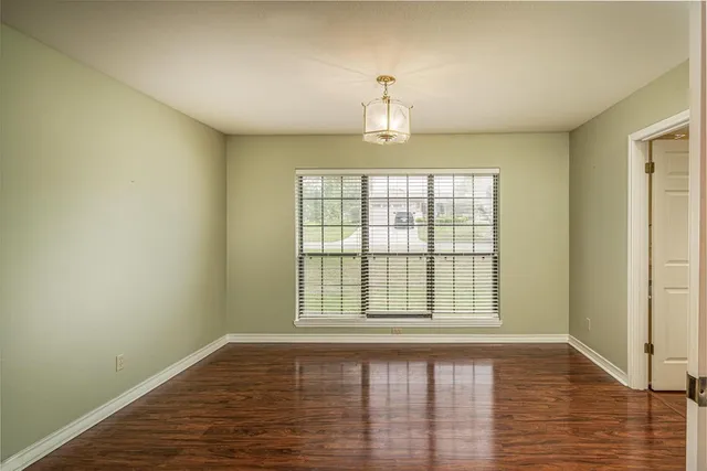 a view of an empty room with window and wooden floor