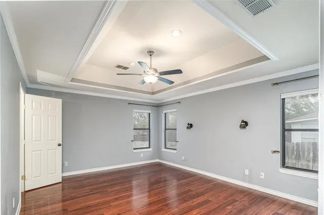 an empty room with wooden floor chandelier and windows