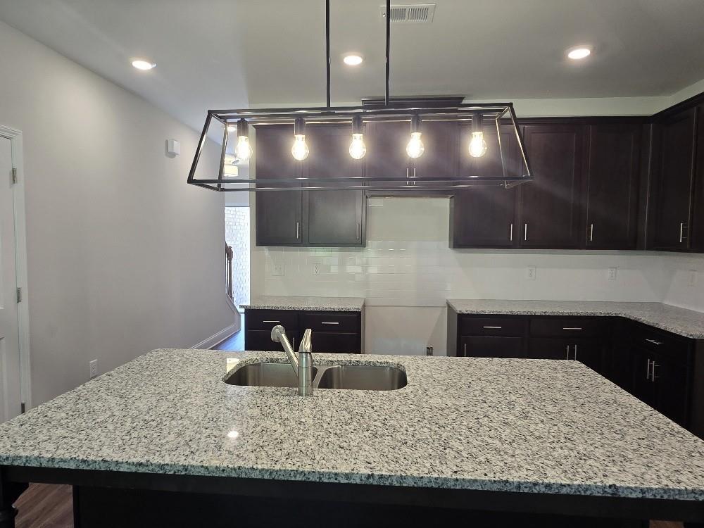6198 Ripple Way, Unit 87 Atlanta, GA 30349 - Photo 7 of 23 a kitchen with kitchen island granite countertop wooden cabinets and granite counter tops