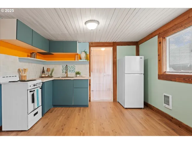 a kitchen with a refrigerator and a wooden floor