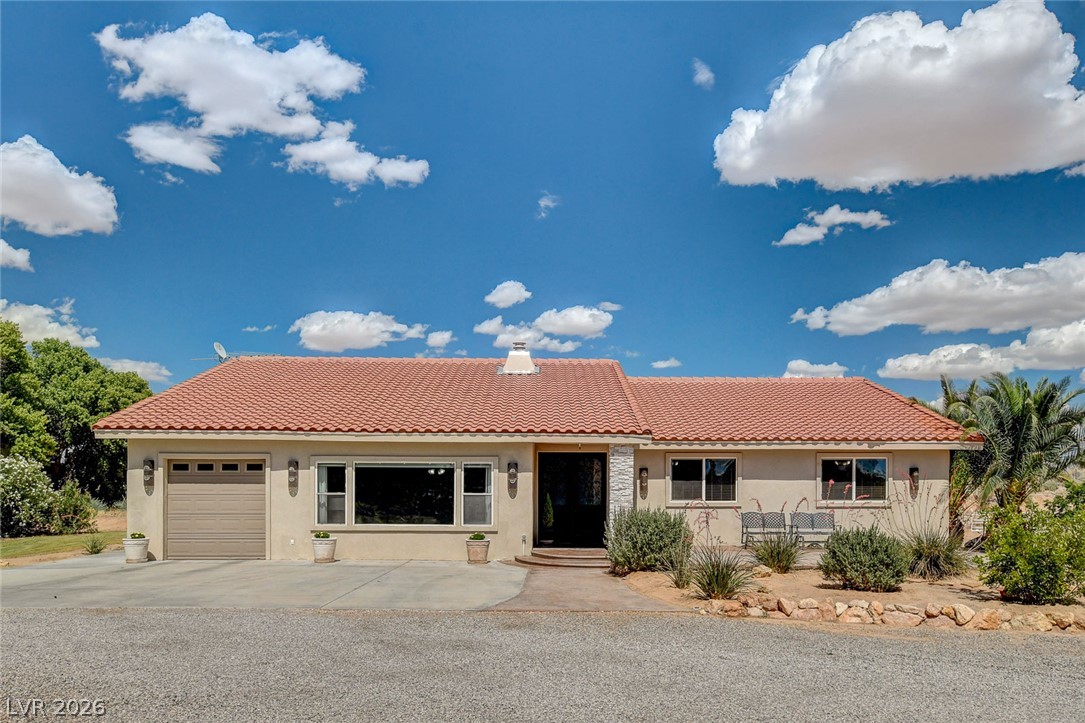 1950 Bowman Road Logandale, NV 89021 - Photo 1 of 81 A terracotta-tiled roof crowns this residence, featuring a single garage door and desert-adapted landscaping.
