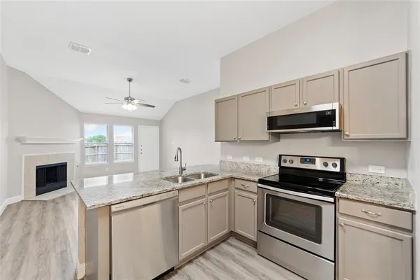 a kitchen with stainless steel appliances granite countertop a sink dishwasher a refrigerator and a oven with wooden floor
