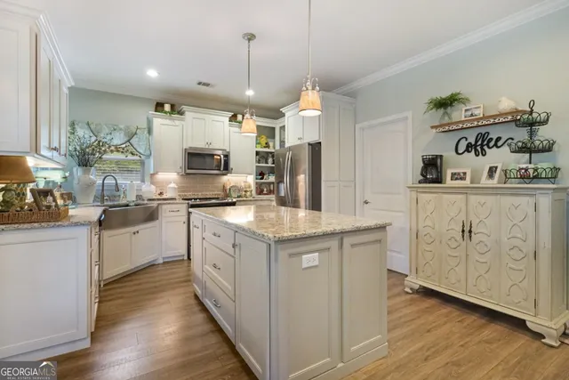 a kitchen with stainless steel appliances kitchen island granite countertop a stove a sink and a refrigerator